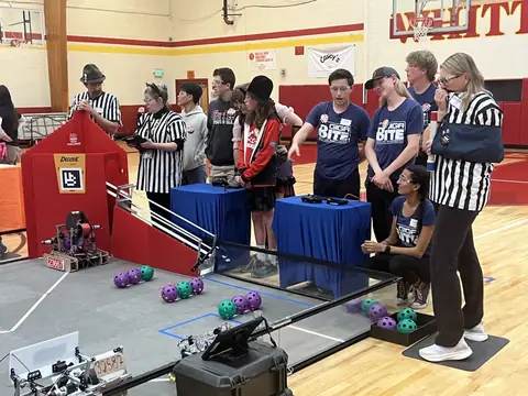 Our robot on the field during a match in the 2025–26 season, with teams and referees looking on.